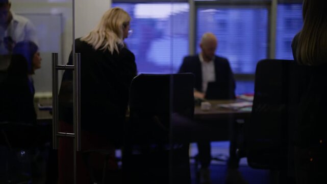 Business professionals convene in a contemporary office meeting room. Colleagues settle around the conference table, ready for their discussion.