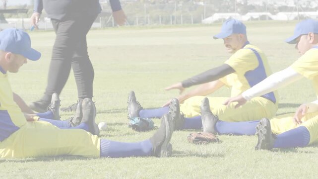Baseball team sitting, reaching cleats after coach walking between them, warming up bands crossing