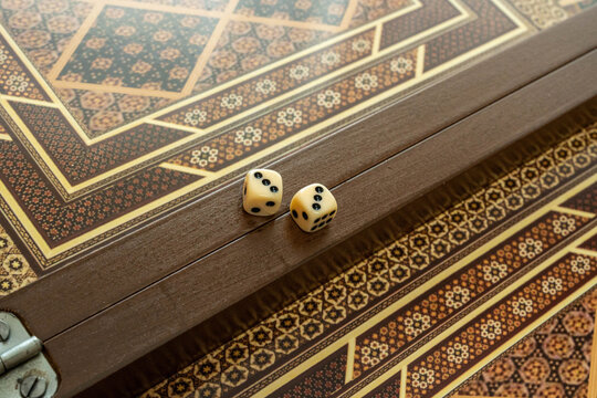 Macro Wooden Dice And Checkers, Ornate Backgammon Board With Intricate Inlay, Warm Sunlight Highlights Brass Corner, Artisan Tabletop Still Life