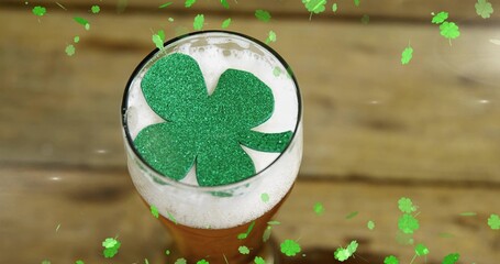 Featuring pint glass of beer sitting on wooden tabletop at pub, with glitter shamrock on foam © vectorfusionart