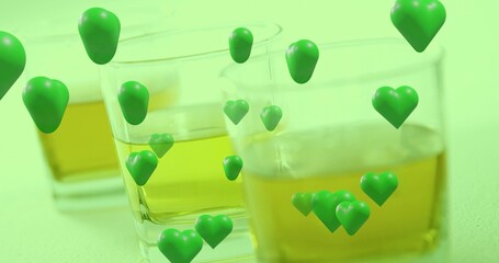 Obraz premium Displaying three square glass tumblers holding amber liquid on studio table, with green hearts
