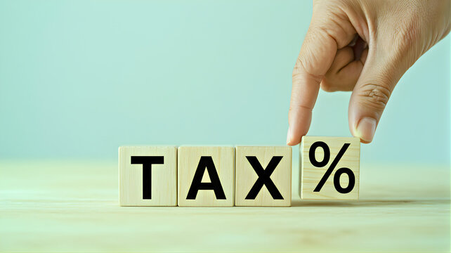 Visual representation of tax rate adjustments and financial planning, with a hand arranging wooden blocks to show 'TAX %', illustrating economic decisions and fiscal policy