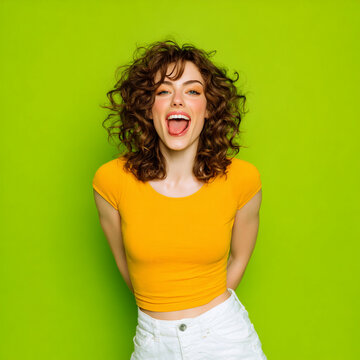 joyful young woman in vibrant green studio portrait, playful stylish female posing with carefree energy, smiling trendy woman portrait on bright green background