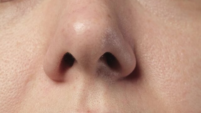 
Close up shot of a Slavic woman demonstrating single nostril movement ability on camera. Rare and unusual human body skill concept.