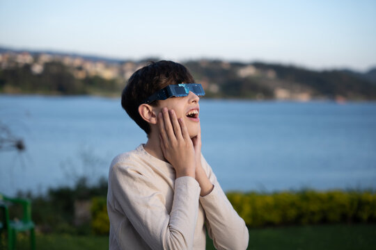 Teenage boy observing solar eclipse with protective glasses outdoors

