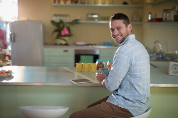 Mint green kitchen counter is basking in warm light with blue mug, tablet, pastries © wavebreak3