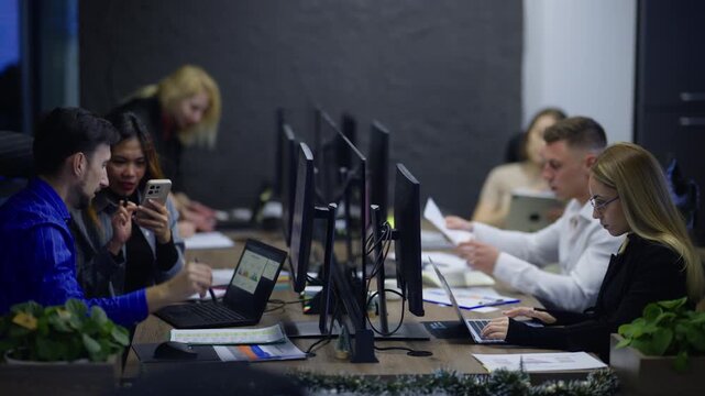 Diverse professionals work together at their desks in a modern office. Colleagues collaborate and concentrate on their tasks in a productive workspace.