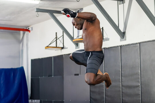Male athlete gloved launching knee strike after jump, animated path showing power in training gym