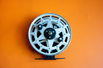 Fototapeta premium Fishing reel sits on orange surface ready for use during fishing trip