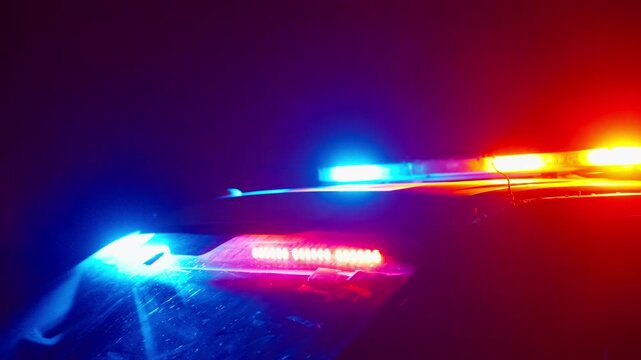 Close shot of police lightbar flashing red and blue at night with motion blur and glowing highlights creating powerful emergency and cinematic mood