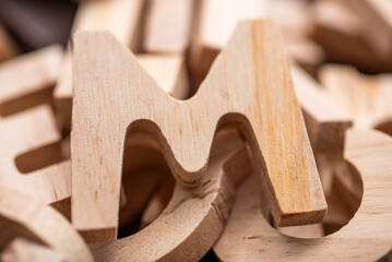 Holzbuchstaben A und M aus hellem Holz. Grob ausgeschnitten. Hintergrund, weitere Buchstaben