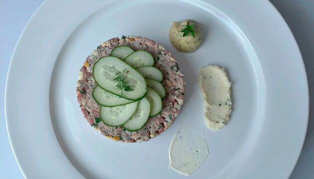 Meat tartare topped with fresh cucumber slices served with herb mashed potatoes on white plate