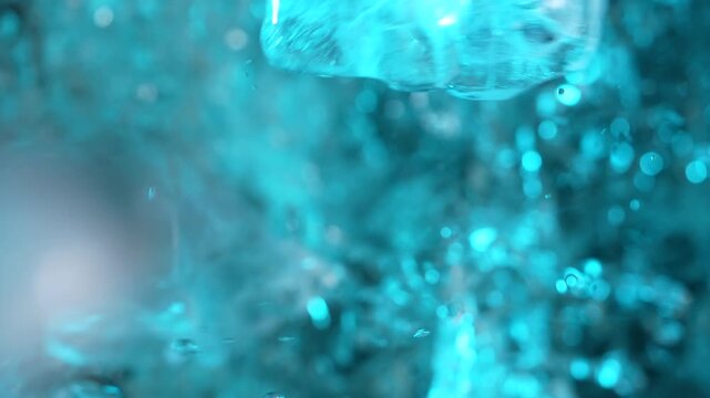 Top view of a ice cubes falling into water with oxygen bubbles, frost patterns, and soft light reflections. Concepts for beauty advertising, menu designs for bars and restaurants, cryotherapy.