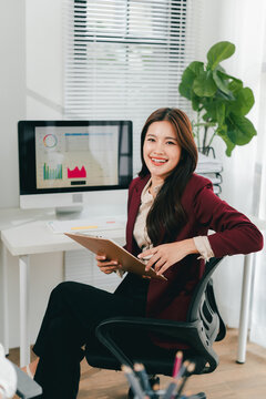 Asian businesswoman holding a tablet in hand looking at the camera Young woman checking business documents, checking accounts, searching for documents, tax, accounting
