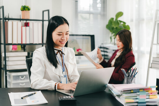 Asian businesswoman holding a tablet in hand looking at the camera Young woman checking business documents, checking accounts, searching for documents, tax, accounting