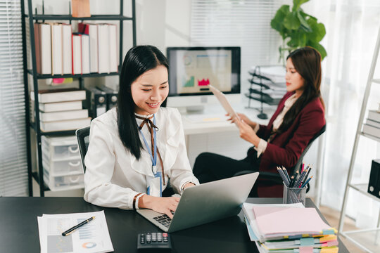 Asian businesswoman holding a tablet in hand looking at the camera Young woman checking business documents, checking accounts, searching for documents, tax, accounting