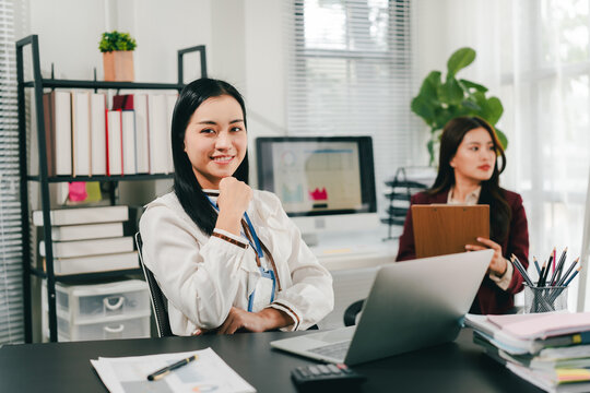 Asian businesswoman holding a tablet in hand looking at the camera Young woman checking business documents, checking accounts, searching for documents, tax, accounting