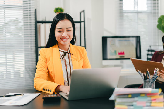 Asian businesswoman holding a tablet in hand looking at the camera Young woman checking business documents, checking accounts, searching for documents, tax, accounting
