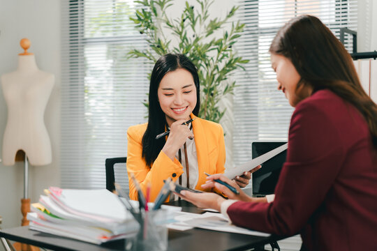 Two female colleagues are consulting and brainstorming. Two female accountants are preparing annual taxes together.