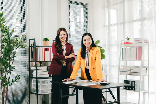 Two businesswomen were having an informal conversation. The two women greeted each other and began discussing a matter.