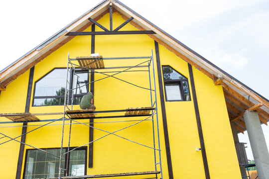 Painted facade with decorative timber boards forming half-timber look, external wall coating, finished plaster layer, color, renovation, final construction step.