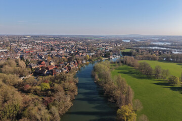 Fototapeta premium Aerial drone view of Reading in Berkshire, England, featuring the River Thames flowing through the town with surrounding urban landscape, bridges, and green spaces.