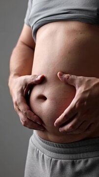 Close-up view of a person's torso, highlighting the physical impact of excess weight, with the person's hands gently supporting the extra weight.