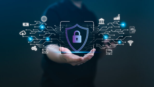 A person holding a virtual shield with a padlock icon over a glowing circuit network. Concept of cybersecurity, data privacy, financial protection, and global digital information safety systems.