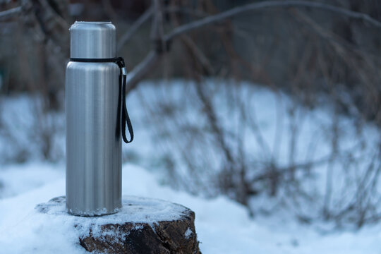 A camping thermos with a hot drink amidst a winter landscape