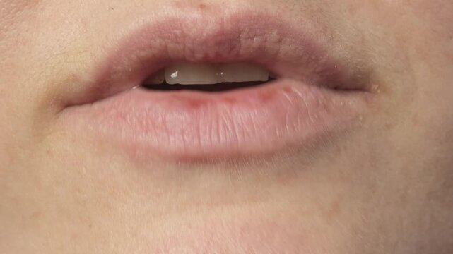 Close up shot of a young caucasian woman mouth speaking silently with no audio. Silent talking, lip movement concept video.