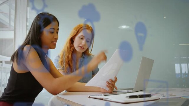 Left woman giving paper to peer, reviewing biz doc at table, blue overlay hovering over document