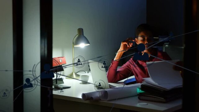 Reviewing files woman in maroon shirt working late at office desk with laptop overlay, copy space