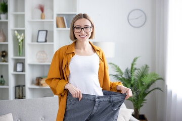 Woman showing significant weight loss holding oversized pants