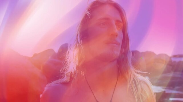 Man turning, gazing toward rocks as sunlight triggers color overlays and lens flare for travel ad