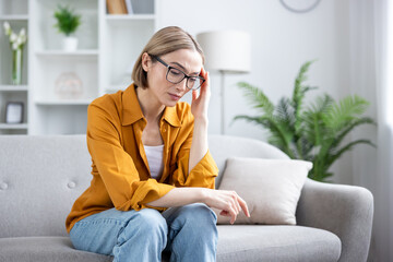 Fototapeta premium Young woman suffering from headache or migraine at home