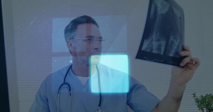 Doctor glancing at monitor then lifting X-ray film, comparing with blue overlay for medical review