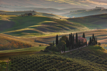 Fototapeta premium Tuscan farmhouse among rolling hills and cypress trees in Val d'Orcia, San Quirico d Orcia, Italy.
