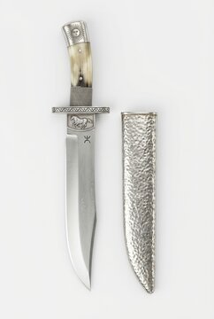 Ornate traditional Argentinian Gaucho Facon knife. Features a sun-engraved silver pommel, bone handle, Damascus blade, and hammered silver scabbard on white.