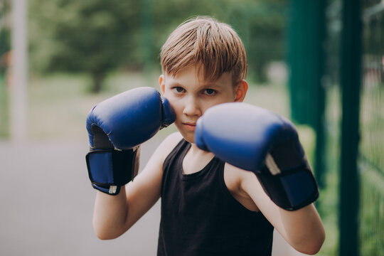 Young boy practicing boxing outdoors in blue gloves