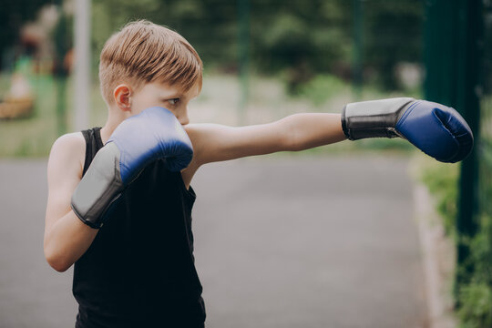 Young boy practicing boxing outdoors with focus