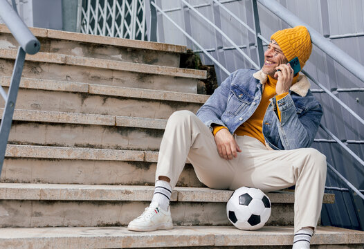 Man with tattoo sitting on stairs talking on phone