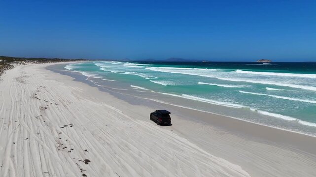 Aerial drone view of a 4WD vehicle with a rooftop tent driving along the coastline near Esperance, Western Australia.