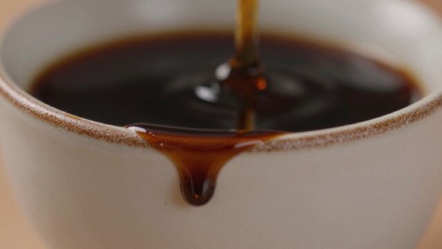 Close-up white ceramic cup brown speckled rim filled dark glossy liquid which appears freshly brewed coffee sl