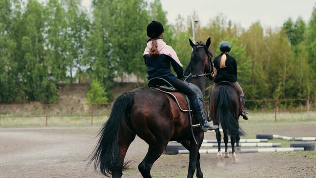 Junior riders exercising with instructor guidance. Horses and students practicing flatwork on overcast day
