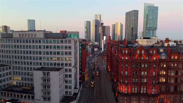 Aerial video over St Peter's Square in Manchester at dawn, featuring yellow trams travelling both ways 
