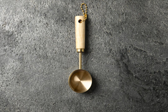 Golden scoop on gray textured table, top view