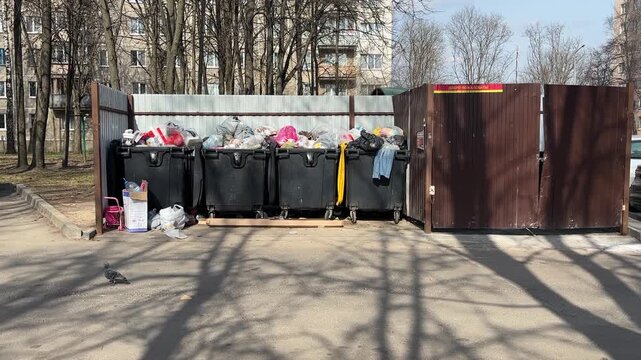 Overflowing garbage bins in residential yard of old apartment buildings