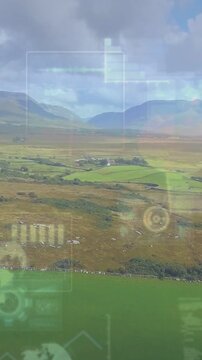 Vertical video: Aerial valley moving over fields, camera tilt causing tech HUD nav overlay on glass