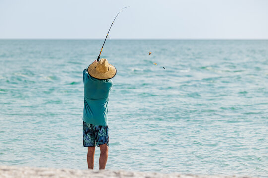 Saltwater fisherman fishing from the beach. Man surf cast fishing from the shoreline of the Gulf of America, Florida.