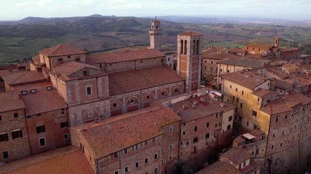 Breathtaking Tuscany Sunrise. Montepulciano aerial 4K. Cinematic drone pull back from old town reveal golden morning hills. Val d'Orcia misty landscape and vineyard. Tuscan epic scenery